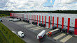© Dark Artistic - Large modern logistics center operating with numerous semi trailer trucks at loading docks, efficiently managing global supply chain distribution and freight transportation