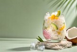 Refreshing tropical fruit drink with ice and coconut on light background