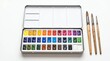 © Mena Bakhet - A professional metal watercolor paint set with assorted brushes arranged on a clean white