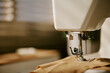 © AnnaStills - Sewing machine needle stitching brown fabric in workshop, representing textile manufacturing and craft hobby. Image suitable for tailoring school promotions, close up shot
