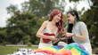 © vittaya - Asian Lesbian Couple Teaching How to Play Ukulele at Park Picnic with Rainbow Flag