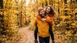 © mdnazirhossain - Happy young couple having fun and piggybacking on a walk in a beautiful golden autumn forest