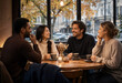 © Sianna - Friendly Gathering Of Four People Enjoying Coffee And Conversation In A Welcoming Café.