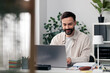 © MexChriss - Man smiling working from home using laptop