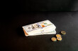 © Oksana - A stack of US hundred dollar bills with euro coins on a dark background a creative concept of money cash savings and income.