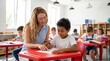 © Eduardo - Professional teacher helping young male student with schoolwork in modern classroom