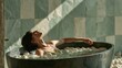 © Bonsales - Young woman relaxing in a bathtub filled with water and smooth white stones, enjoying a tranquil spa moment