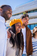 © CarlosBarquero - Vertical. Group of multicultural friends walk side by side through a bright residential district, enjoying friendship, sunshine and an easygoing urban lifestyle.