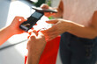 © Studio Marmellata - A customer uses a smartphone to complete a contactless payment at a retail store. The shop assistant hands over a red shopping bag after the successful transaction.