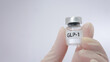 © Piya W. - Hand holds small glass vial for glp 1 injection bring hopeful mood for medical weight loss treatment on clear white background
