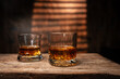 © aekachai - Whiskey Glasses with Ice Cubes on Wooden Table in Warm Sunlight