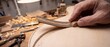© Lumo - Skilled hands carefully pressing decorative herringbone marquetry purfling into carved groove of light spruce acoustic guitar soundboard