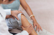 © Natee Meepian - Physiotherapist holding senior woman knee during joint assessment at home