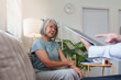 © Natee Meepian - Doctor showing digital tablet to senior Asian woman during home medical checkup