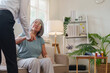 © Natee Meepian - Healthcare worker assisting senior Asian woman to stand up from sofa at home