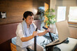 © Davor - Woman on exercise bike following workout on laptop in home bedroom