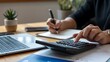 © Soyaeb - Professional accountant managing budget and financial planning using calculator and notebook in an office setting