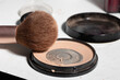 © olga_sova - Close-up of a worn makeup brush resting on an open beige compact with powder dust and residue, conveying authentic, unpolished use while highlighting shelf-life, hygiene, and daily routines.