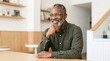 © NimVisuals - Smiling mature African American man relaxing in a modern cafe setting.