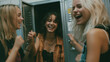 © RB - Three joyful teenage girls laughing together while standing in front of metal school lockers during break