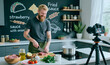 © AnnaStills - Caucasian young adult man filming cooking tutorial while chopping raw meat in home kitchen, creating food content for social media marketing, medium shot