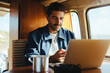 © Julia - Working on the road: Man using laptop inside a camper van