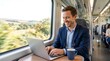 © xuxu - Smiling man working on laptop inside train by window. Business travel and remote work concept. Businessman commuting and using computer during railway journey
