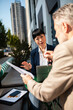 © Davor - Business colleagues discussing a financial report at an outdoor city cafe