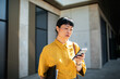 © Davor - Businesswoman checking smartphone outside office building