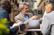 © Davor - Business team discussing reports at outdoor cafe