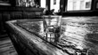 © Jam - Single glass of whiskey resting on a worn wooden bar counter inside a quiet pub during the day