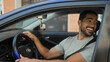© Krakenimages.com - Man at steering wheel with hand on wheel turning head and reaching for rearview mirror on street; casual friendly moment.