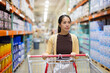 © leungchopan - Woman shopping with cart in wholesale retail store