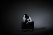 © HaXuanDieu - Depressed man sitting alone in chair under dramatic light