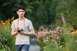 © HaXuanDieu - Young man with camera in a flower garden path outdoors