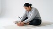 © Ramdani - Woman experiencing foot pain while sitting on a yoga mat