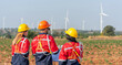 © BESTIMAGE - Team workers training wind turbine power generator sustainability performance brainstorming together at Renewable Energy Plant Back view of three engineers holding blueprint inspecting windmill