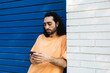 © ADDICTIVE STOCK - Man use smartphone beside blue wall in city