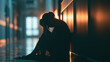 © stock by siam - A silhouette of a depressed person sits in a dark hallway with dramatic backlighting. Ideal for mental health awareness campaigns.
