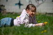 © Christina - Little girl lying on the grass with dandelions. Childhood in Nature. Young girl lying in a green meadow and enjoying a peaceful moment outdoors. Carefree childhood moments.