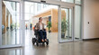 © Rathnayaka - Professional Woman Using Motorized Wheelchair Entering Modern Corporate Building Through Automatic Glass Door Accessible Workplace