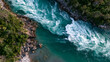 © Exclusive collection - Aerial view of a turquoise river flowing through a rocky canyon with lush green forest. This powerful water flow represents energy and wild nature concepts.