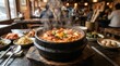 © mila103 - Steaming hot stew served in stone pot on restaurant table
