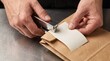 © Geetha - Close up hands stapling blank receipt to bag, commercial ghost kitchen packaging, food delivery order fulfillment, virtual restaurant preparation, macro detail