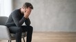 © DhimasPratama - stressed man covering face with hands sitting on chair mental health depression and anxiety concept
