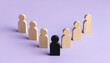 © The Stock Hub - Standing out from the crowd concept with wooden figures and one black figure on purple background