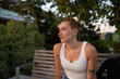 © Metadancer - A young white woman sits on a wooden bench outdoors in Santiago
