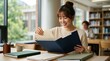 © Len_mik - Young Asian female student organizing documents in blue folder. Smiling woman sorting papers at library table. Education and organization concept
