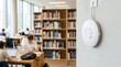 © Nazlykhan - White wifi access point mounted on wall in modern library with blurred student studying on laptop. Wireless internet connectivity and digital education technology concept