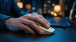 © Sangad - A person working on a laptop at a desk with blue ambient lighting and a hand resting on a white computer mouse.